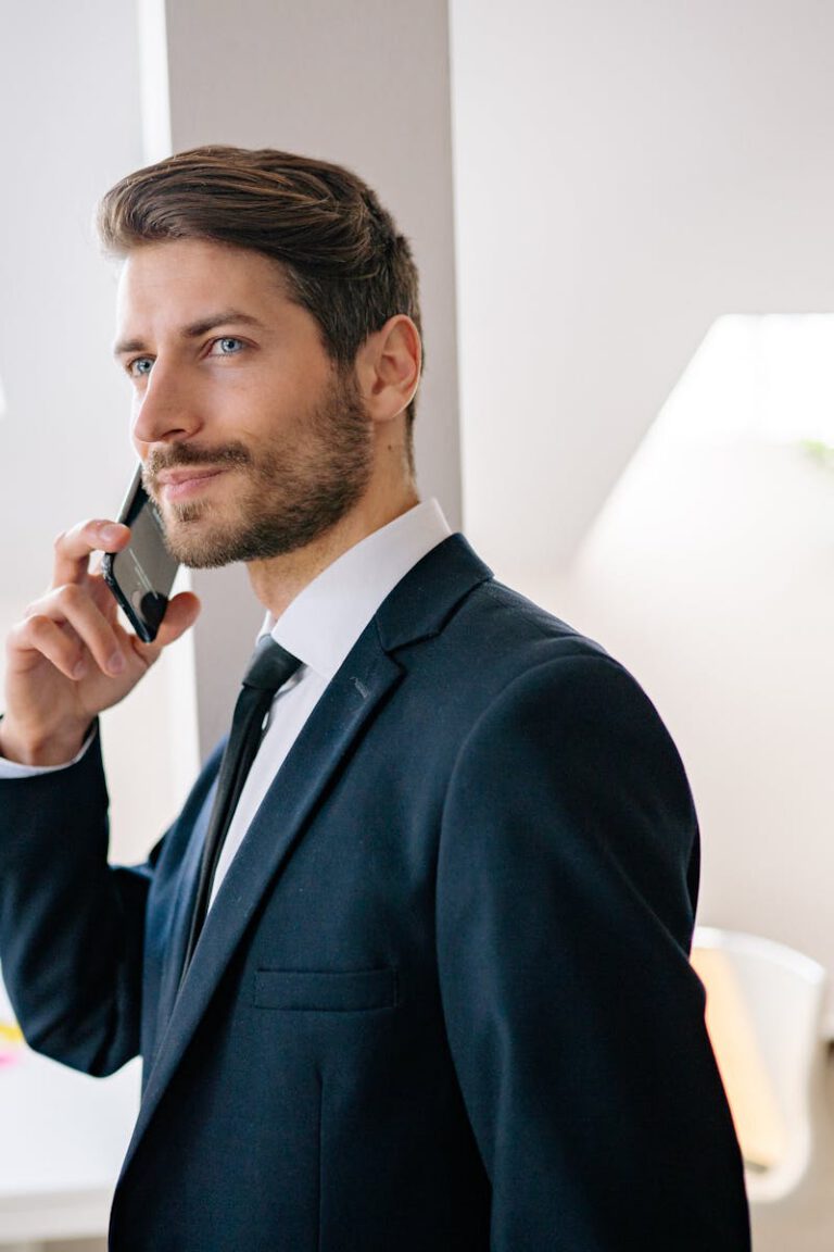 Professional businessman in a suit making a phone call in a modern office setting.